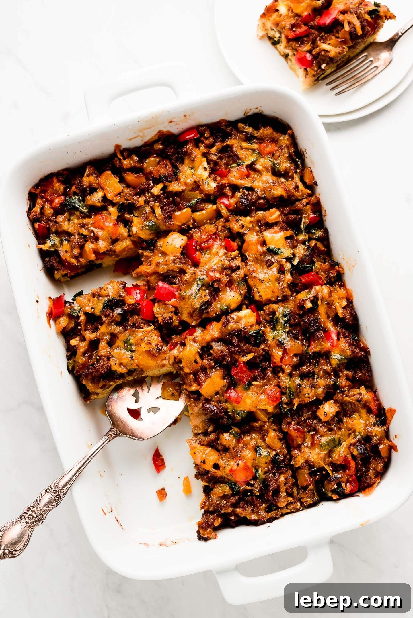 White dish of squares of egg and sausage breakfast casserole.