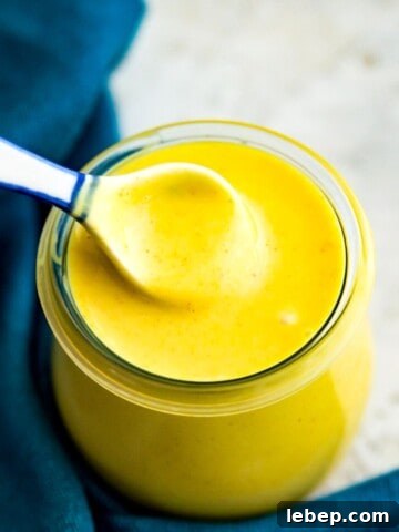 A jar of honey mustard sauce with a spoon in it.