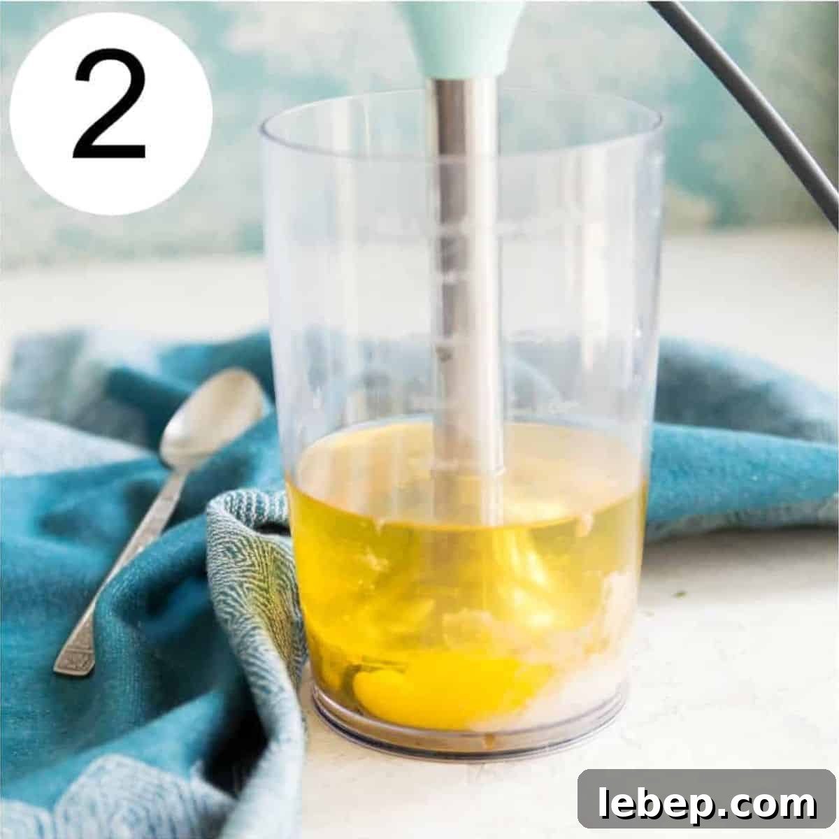 Creamy Immersion Blender Mayonnaise Recipe in Minutes 5 A clear jar with an immersion blender in it blending oil and vinegar.