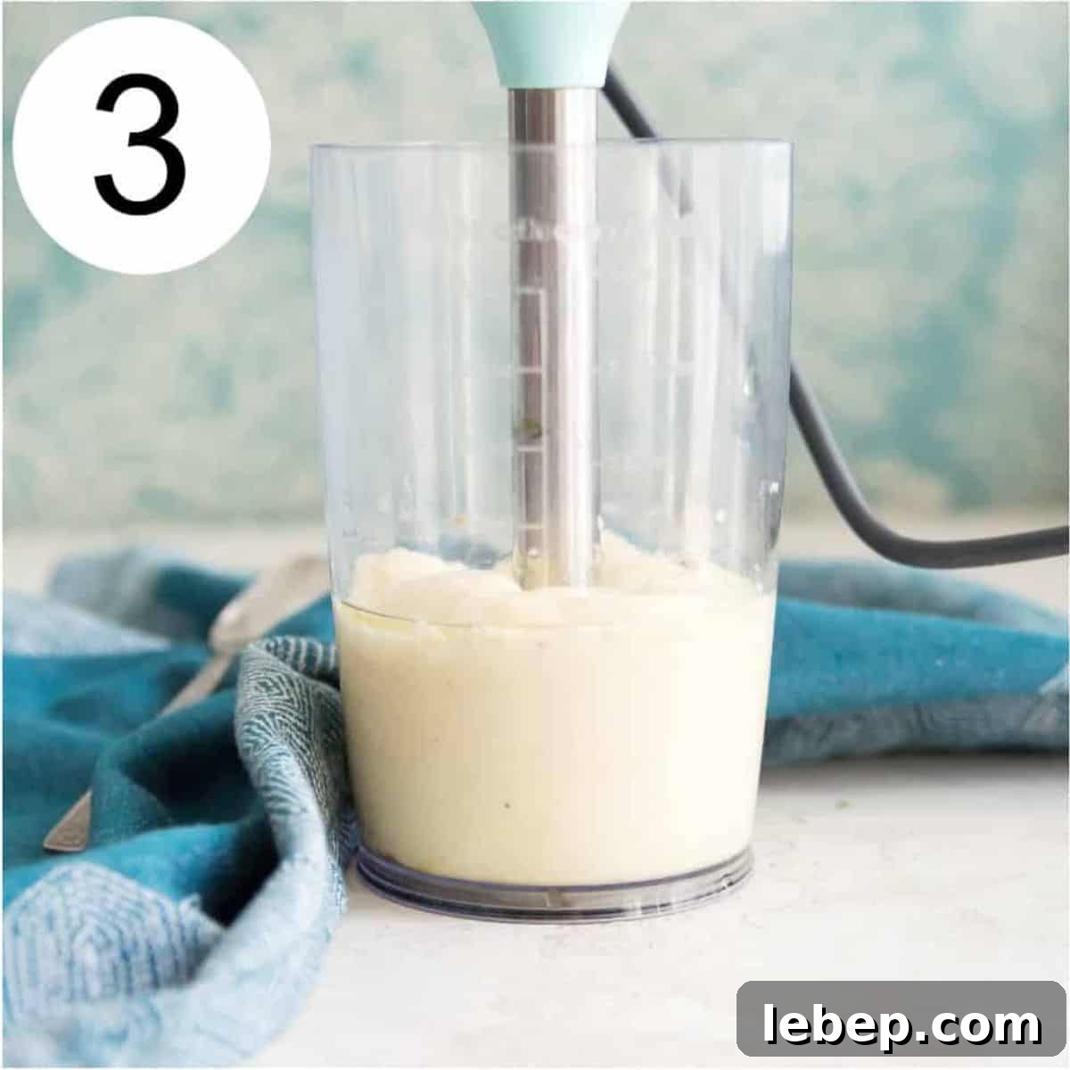 Creamy Immersion Blender Mayonnaise Recipe in Minutes 6 A clear jar with an immersion blender in it blending a thick, creamy white liquid.