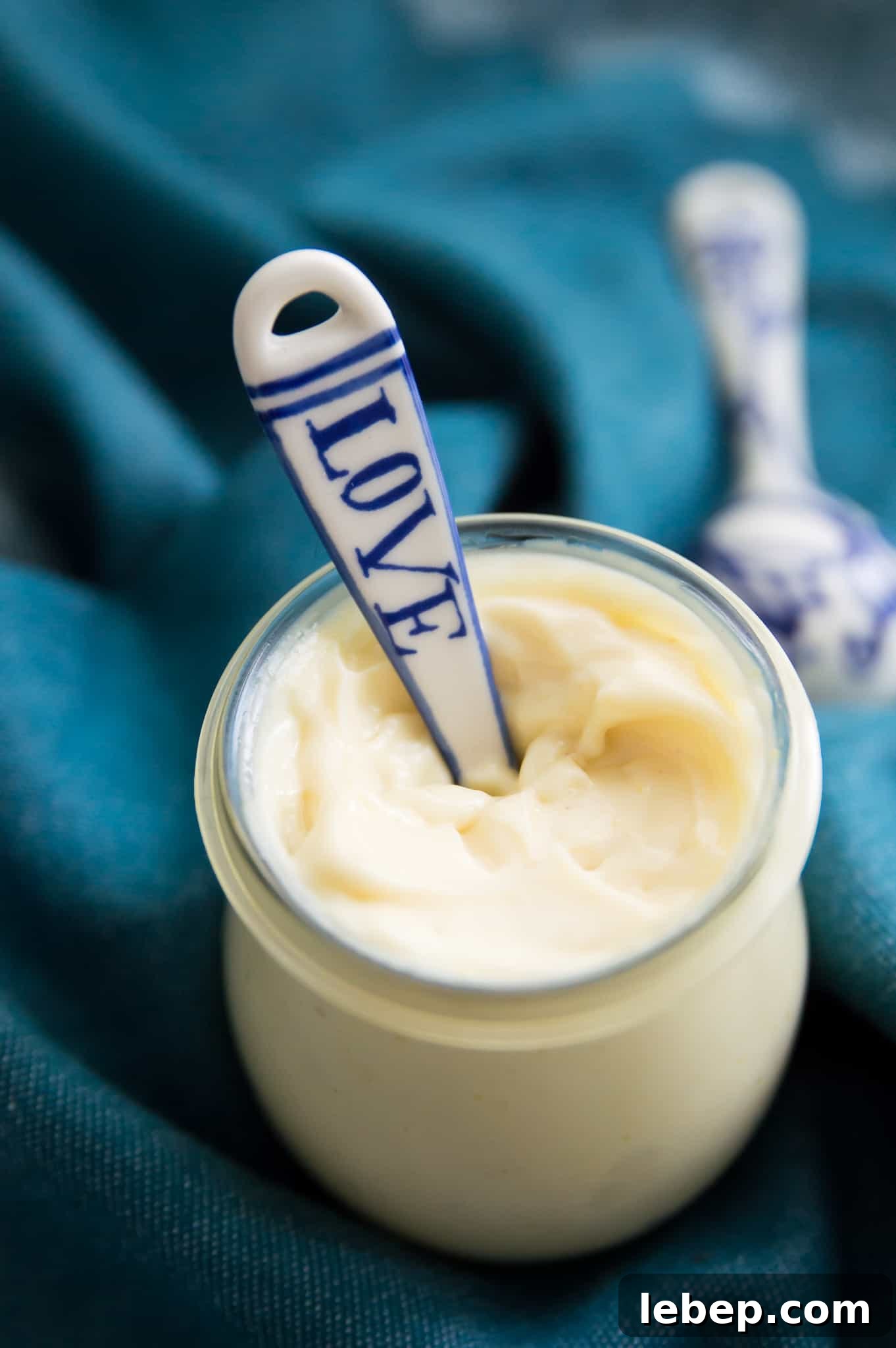Creamy Immersion Blender Mayonnaise Recipe in Minutes 8 A glass jar with mayonnaise in it with a spoon in the mayonnaise.