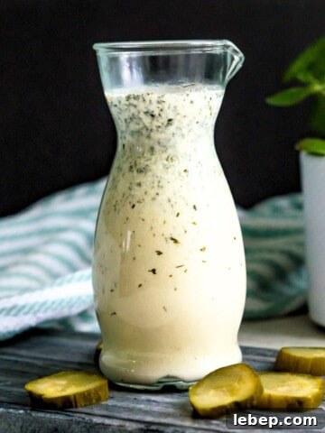 A bottle of dill pickle salad dressing with cut up pickles beside it.