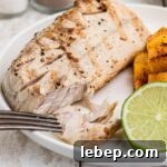A close up of a fillet of Grilled Cobia with a fork digging in.