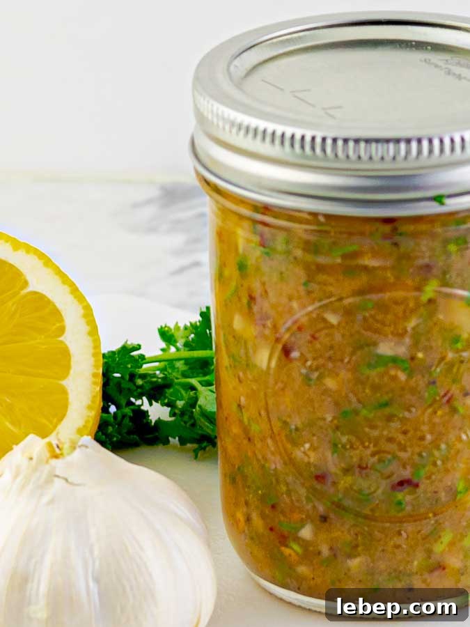 Zesty Homemade Italian Dressing Recipe for Fresh, Tangy Flavor 5 mason jar of Homemade Zesty Italian Dressing with a lemon, garlic, and parsley
