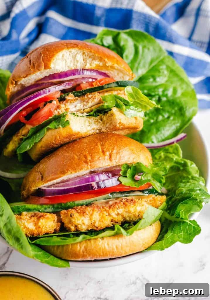 Crispy Fried Chicken Sandwich Recipe with Tangy Slaw 19 Two crispy chicken sandwich in a bowl with one with a bite taken out of it.