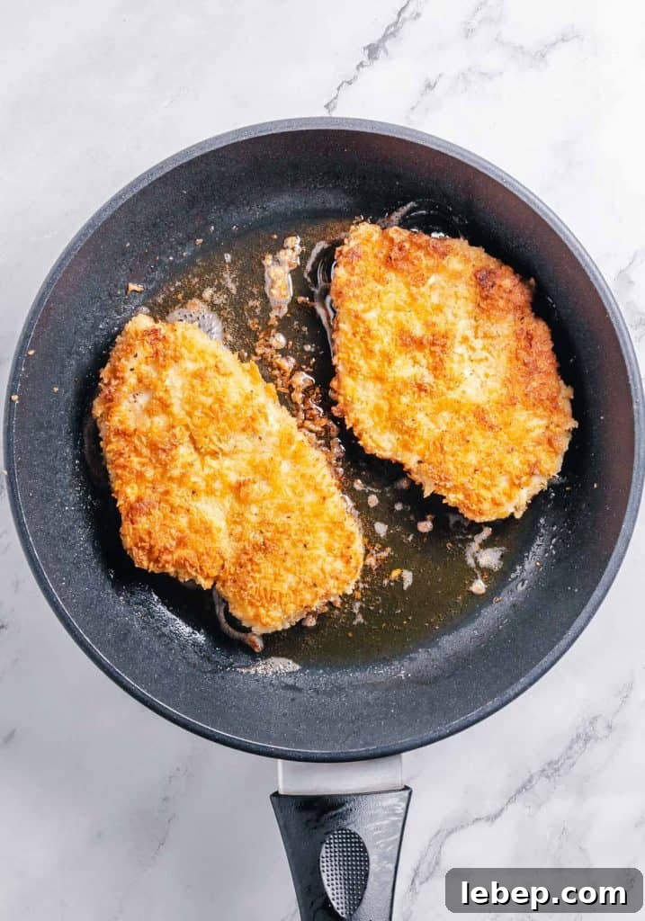 Crispy Fried Chicken Sandwich Recipe with Tangy Slaw 10 Fried chicken cutlets in a pan.