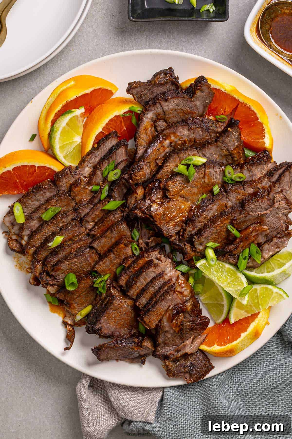 Citrus-Soy Braised Chuck Roast Recipe: Tender, Flavorful Pot Roast 2 A close up of a platter with braised chuck roast sliced thin garnished with orange and lime.