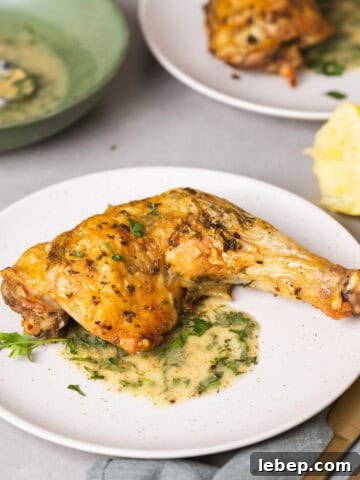 A serving of golden brown roasted chicken leg quarters with an herb sauce
