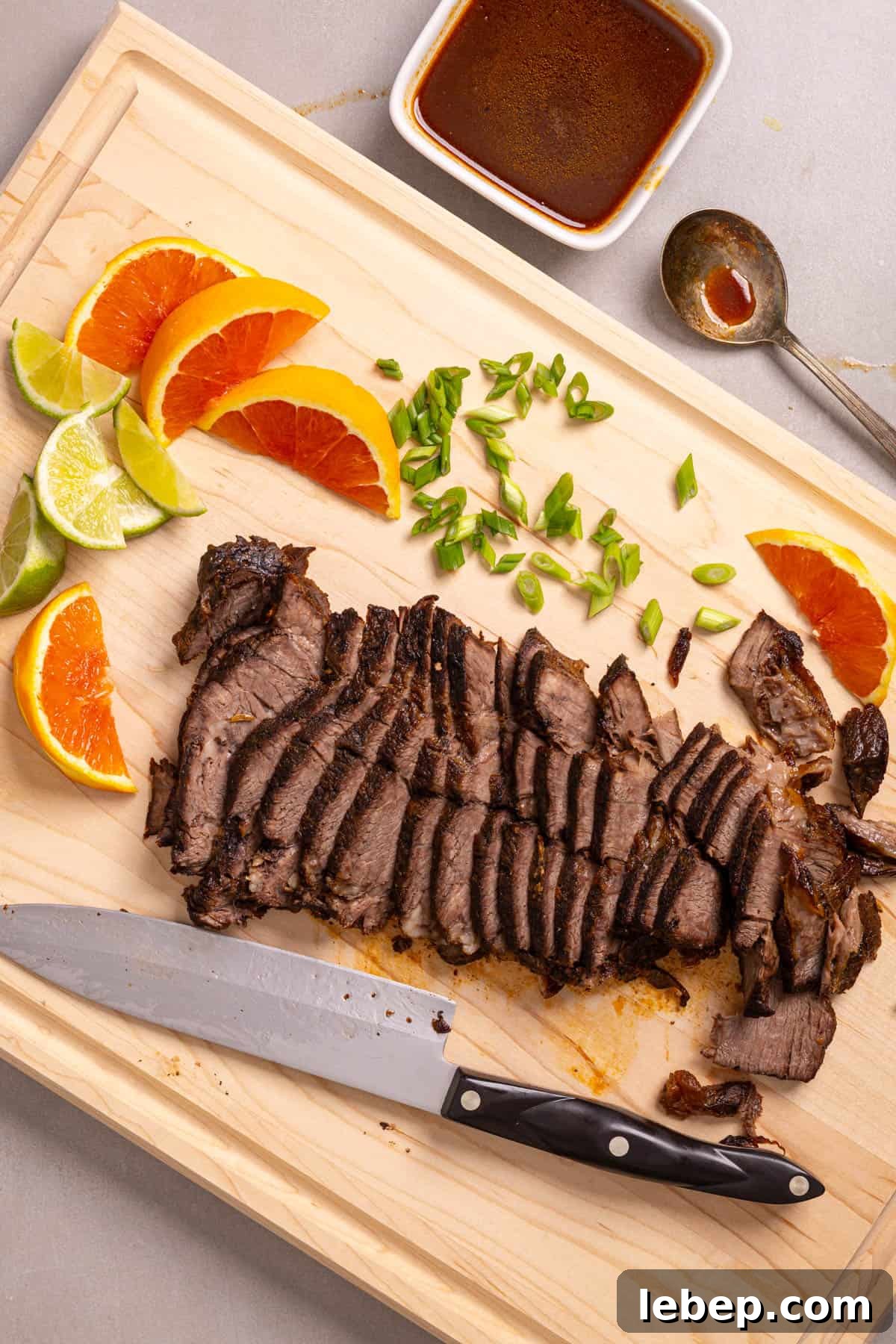 Citrus-Soy Braised Chuck Roast Recipe: Tender, Flavorful Pot Roast 8 A cutting board with sliced of orange and lime, scallions, and braised chuck roast.