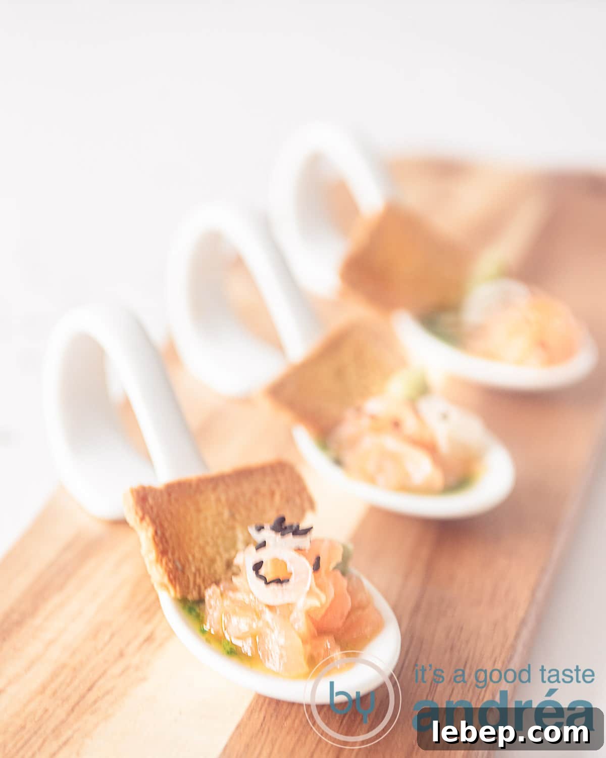 Salmon Amuse-Bouche with Arugula Oil Dressing 2 An elevation photo, three amuse-bouche spoons in a row filled with arugula oil, salmon and a toast