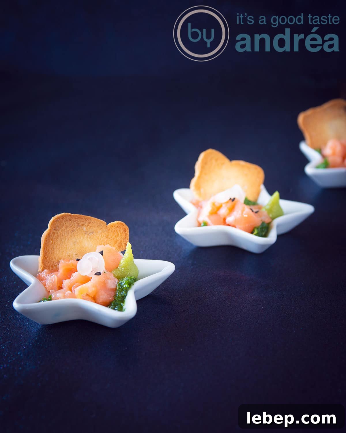 Salmon Amuse-Bouche with Arugula Oil Dressing 5 Three amuse bouche star plates filled with smoked salmon, arugula oil and onions on a blue background