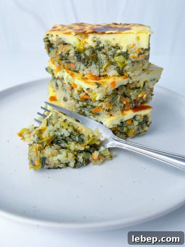 Cheesy Oven-Baked Rice Casserole Recipe for Family Dinners 2 Three stacked slices of oven baked rice casserole with a golden top, served on a white plate with a fork and a small portion of the casserole next to the stack.