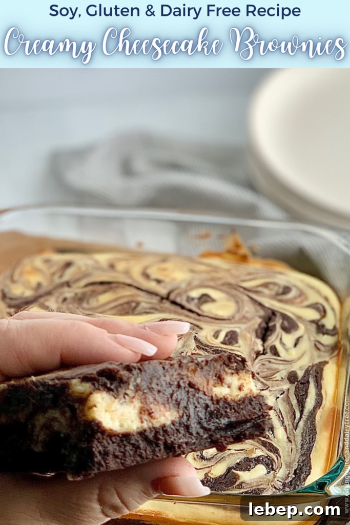 Decadent Cheesecake Swirl Brownies — Rich Chocolate & Cream Cheese 2 A person folding a cut out brownie with chunks of white cream cheese in it with an 8x8-inch baking dish filled with a baked marbled brownie mixture with swirls of cream cheese and dessert plates in the background.