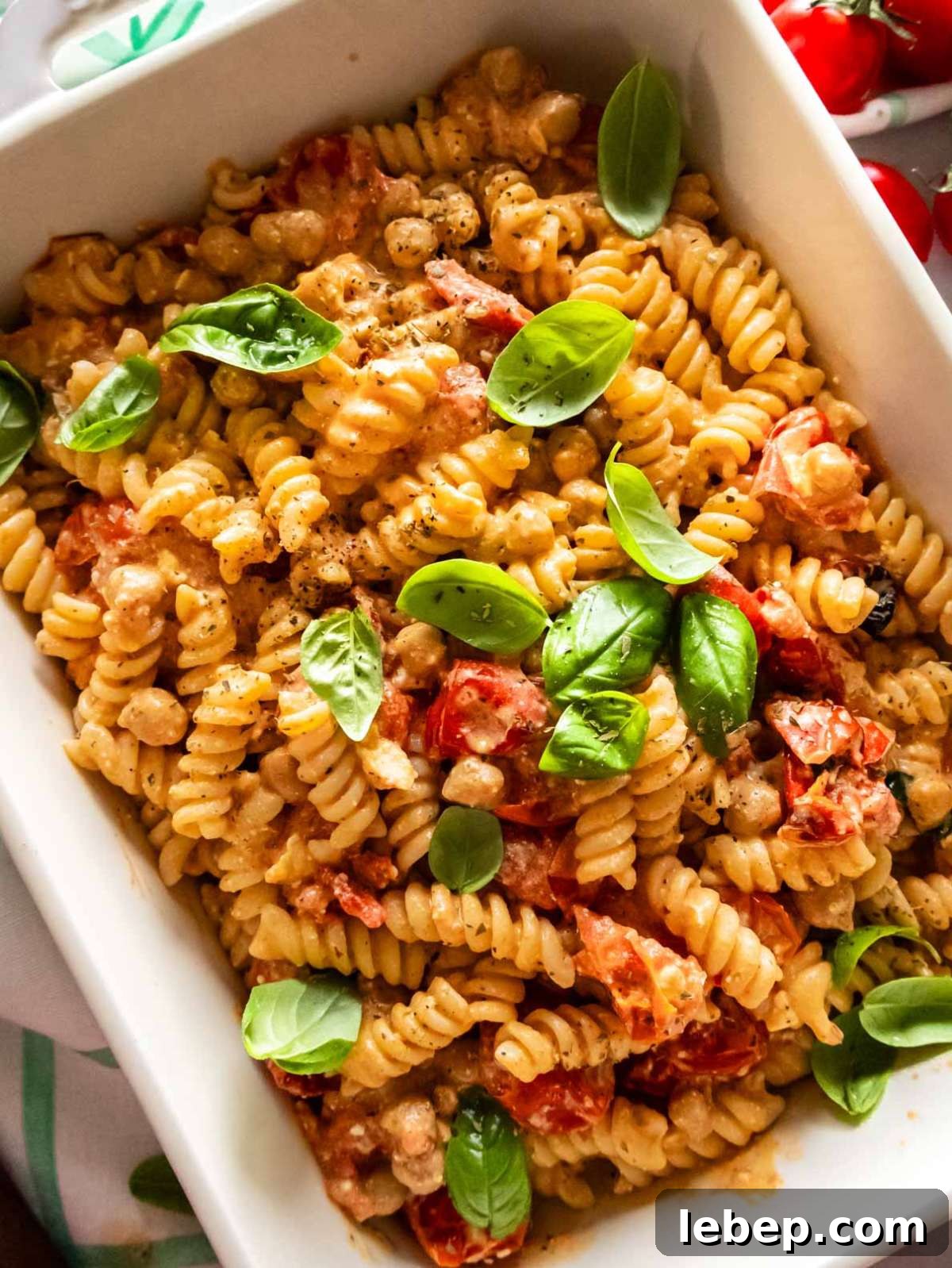 Baked feta pasta with chickpeas and cherry tomatoes in white baking dish.