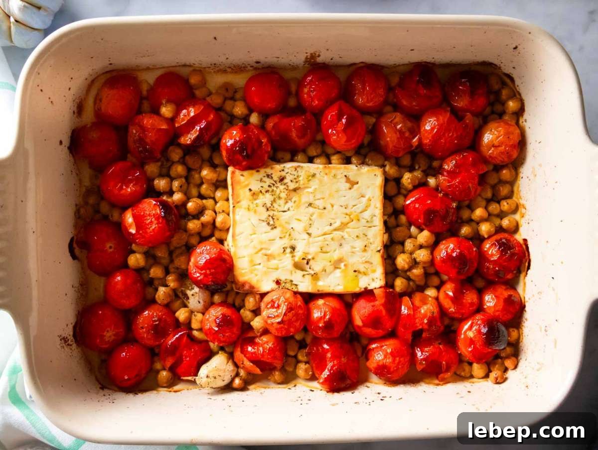 Cherry tomatoes chickpeas and feta arranged in baking dish before roasting.