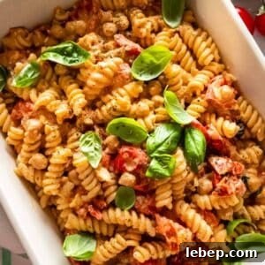 Baked feta pasta recipe served with basil lemon zest and olive oil on rustic table.