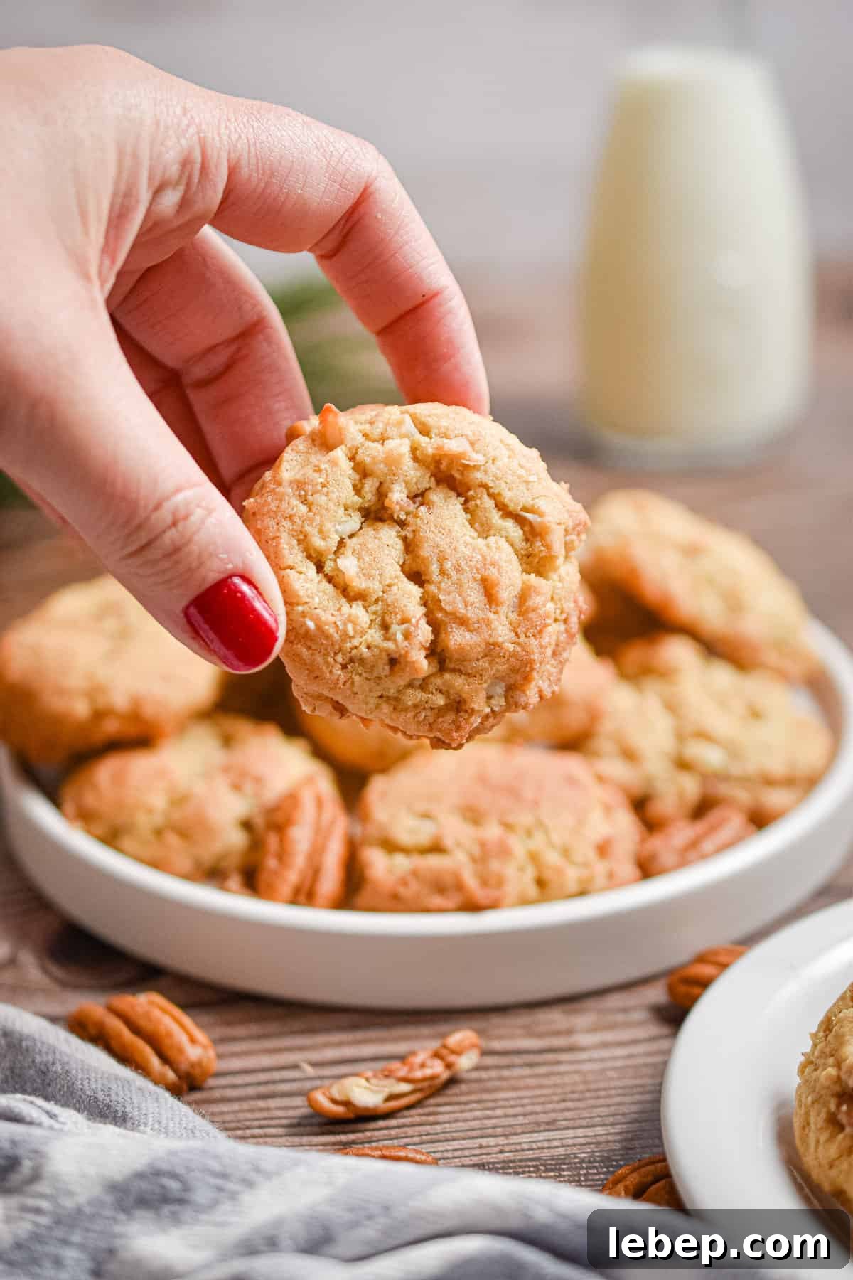 Chewy Coconut Pecan Cookies Recipe — Crispy Edges & Gooey Center 10 A hand is holding a coconut pecan cookie.