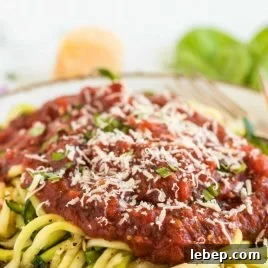 close up shot of a plate of Zucchini Noodles served with salsa and parmesan cheese on top