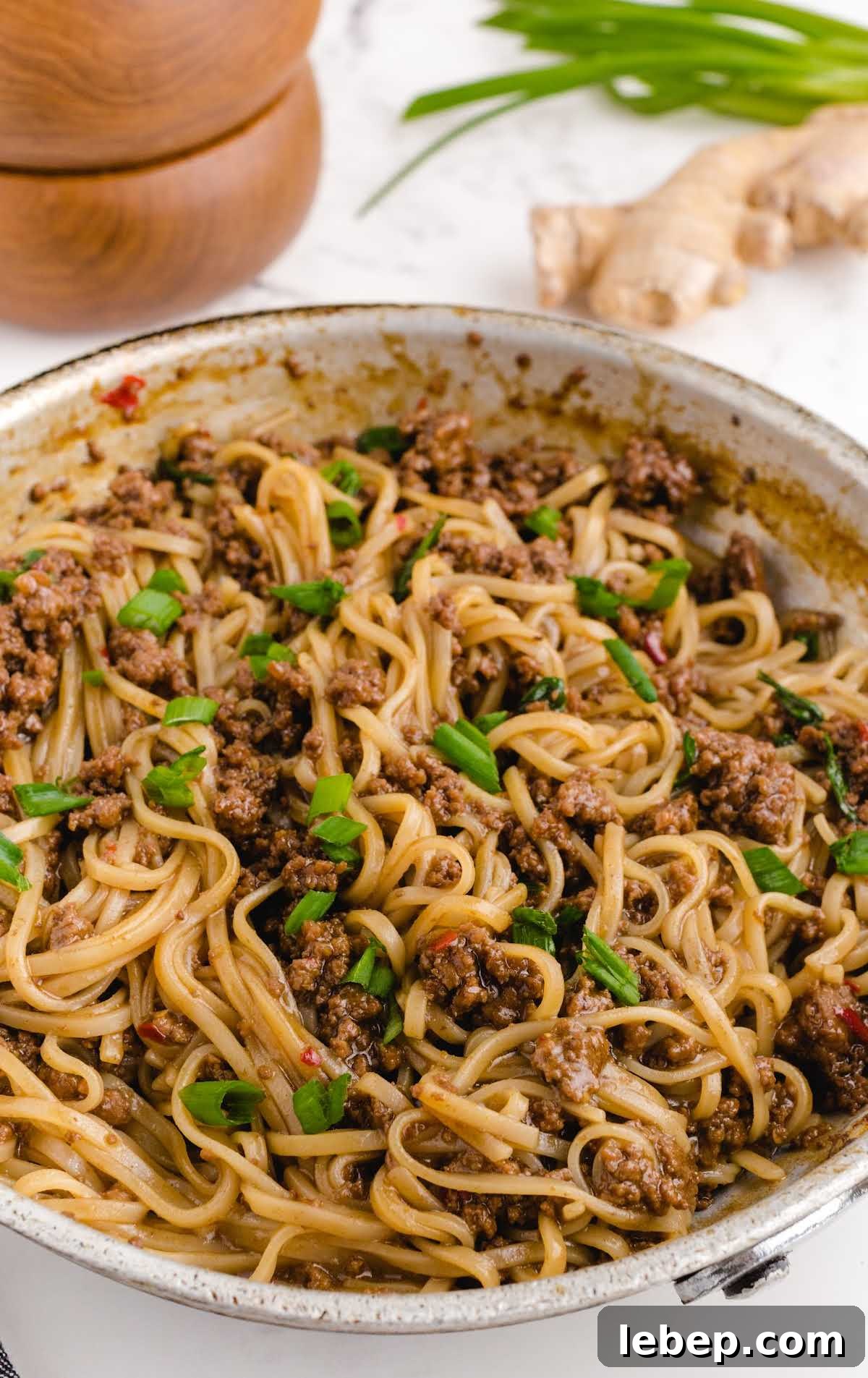 close up shot of a skillet of Mongolian Beef and Noodle Recipe garnished with green onions