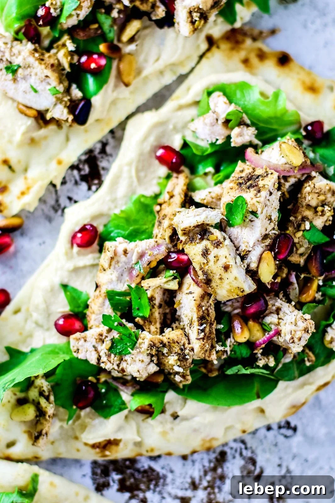 Sheet-Pan Za'atar Chicken on Naan: Quick Flavorful Dinner 2 Close up of naan breads topped with hummus, chicken, and greens.