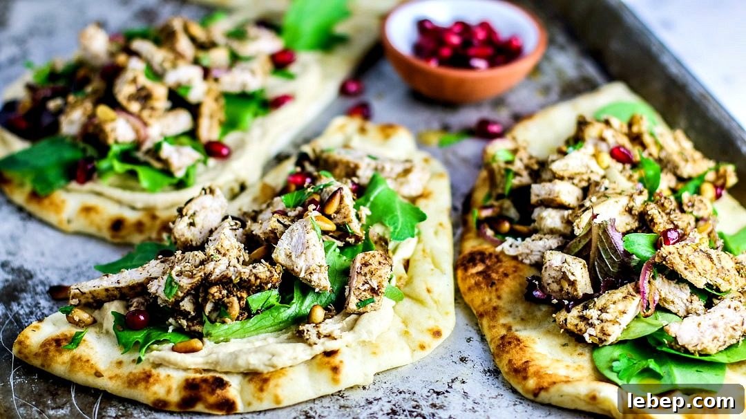 Sheet-Pan Za'atar Chicken on Naan: Quick Flavorful Dinner 3 Naan breads topped with hummus, chicken, and greens.