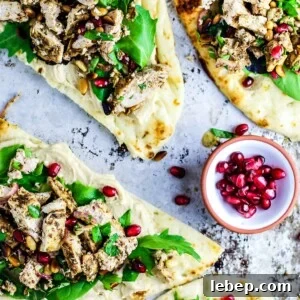 Naan breads topped with hummus, chicken, and greens.