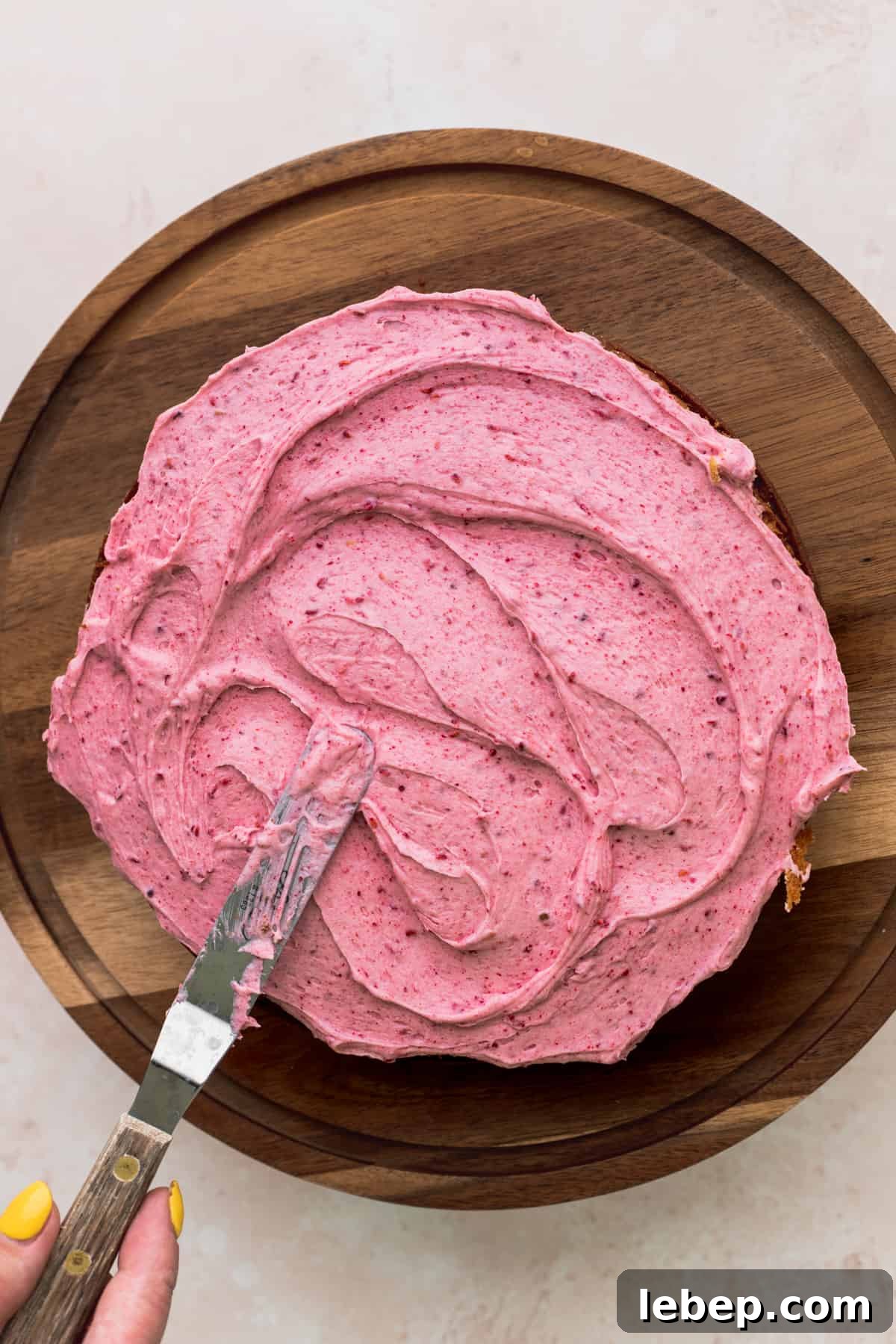 Spreading raspberry frosting over a cake.