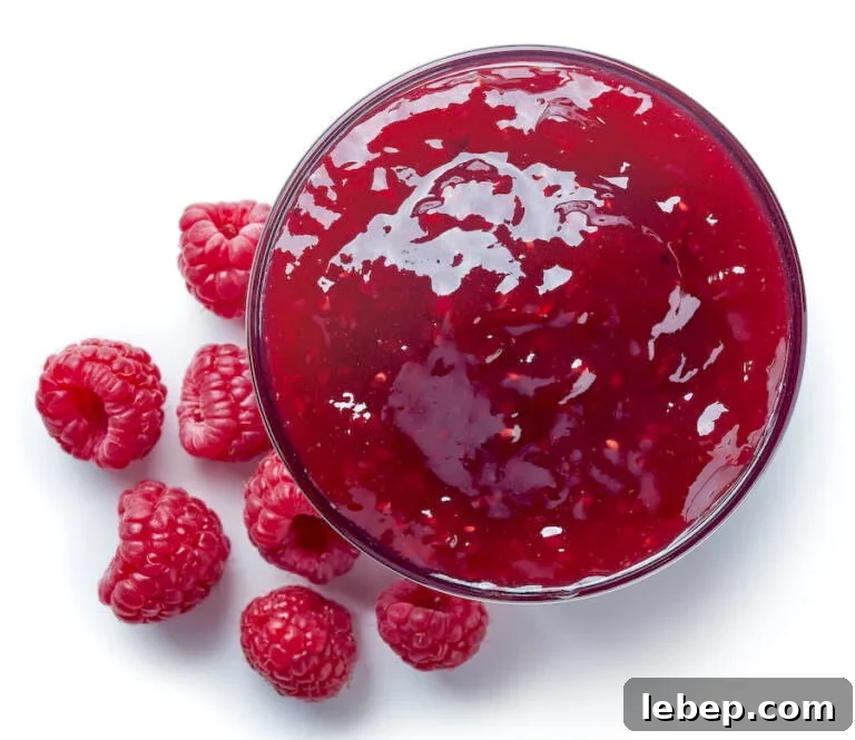 Raspberry Jam in jar with fresh raspberries strewn about