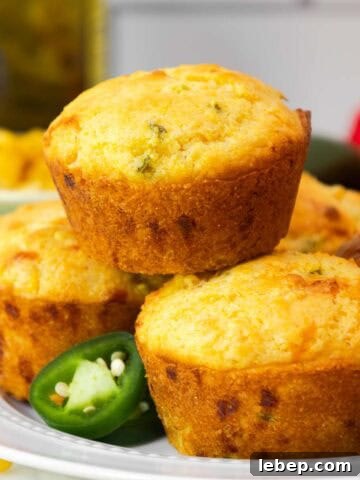 Close-up of a jiffy jalapeño cornbread muffin on a plate, with a focus on its golden crust and specks of jalapeño inside.