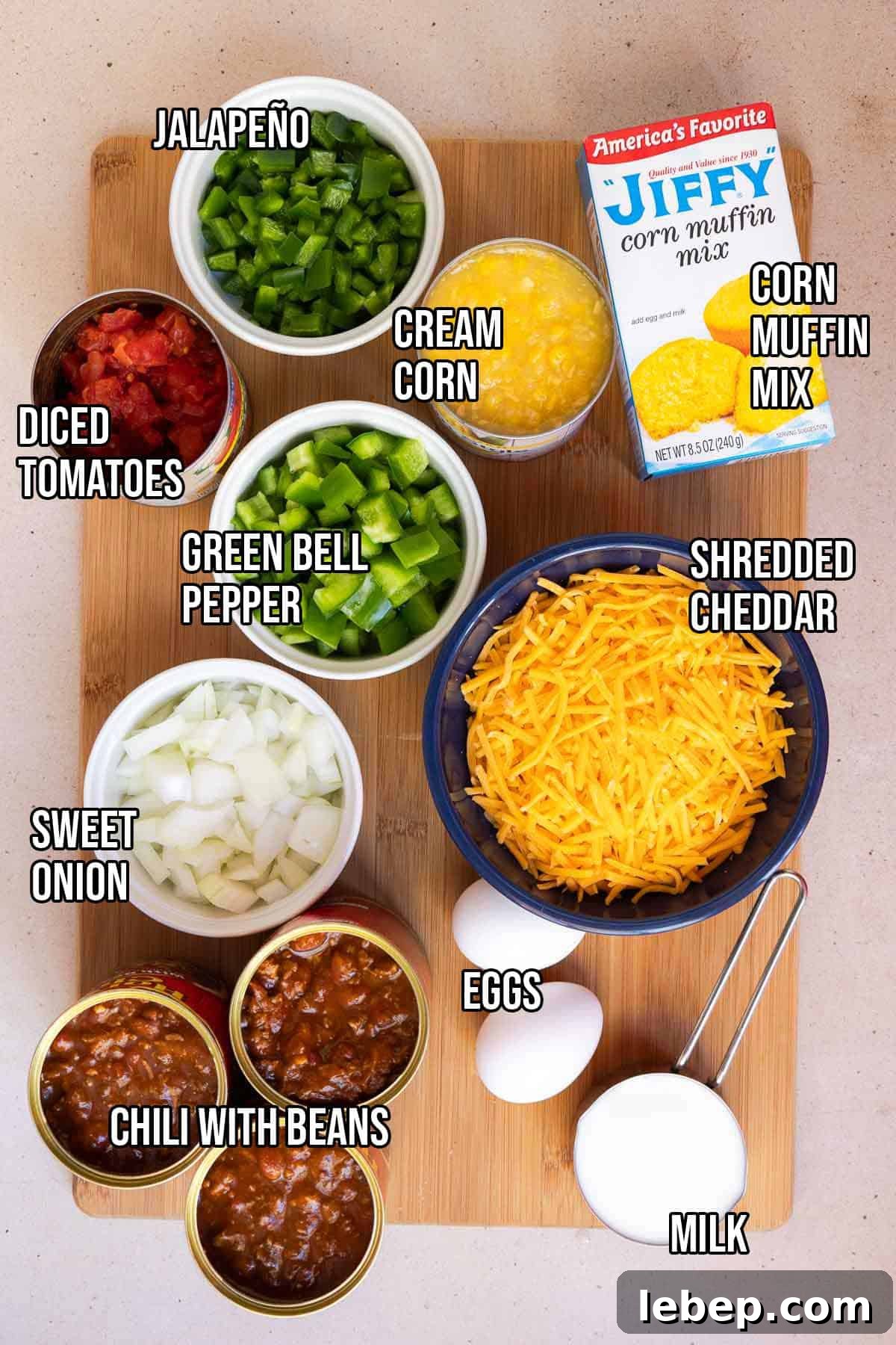 Canned Chili Cornbread Casserole Recipe for Quick Weeknight Dinner 4 Chili cornbread casserole ingredients including canned chili with beans, fresh jalapeño, canned diced tomatoes, diced green bell pepper, diced sweet onion, shredded cheddar, a box of Jiffy corn muffin mix, canned cream style corn, eggs, and milk.