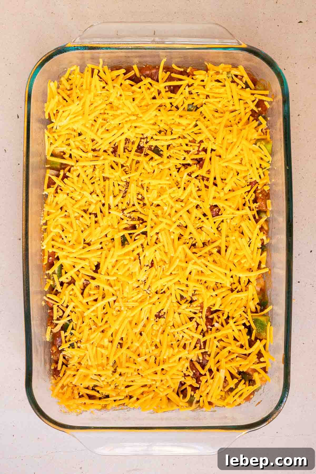 Canned Chili Cornbread Casserole Recipe for Quick Weeknight Dinner 7 Shredded cheddar is sprinkled evenly over the chili.