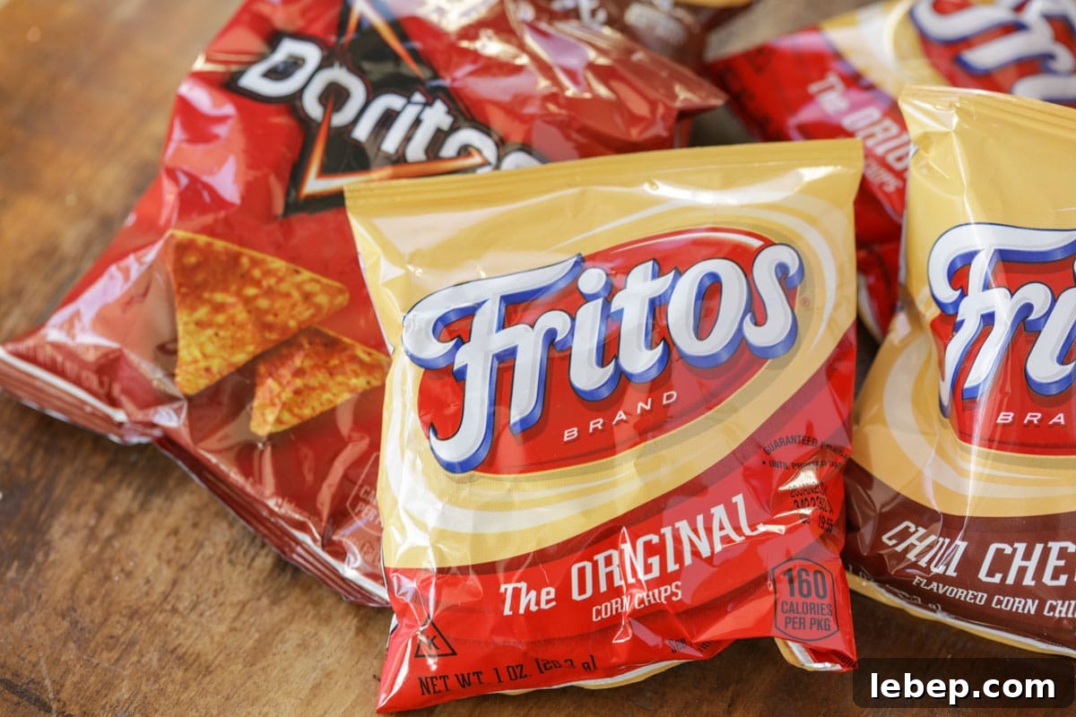 Walking tacos are an easy grab-and-go meal that is full of flavor! They are no mess, easy to make, and perfect for large gatherings!! Small bags of fritos and doritos on a table.