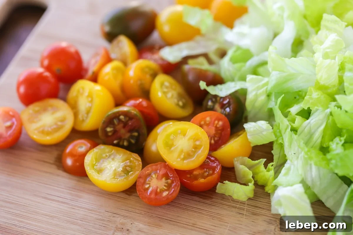 Walking tacos are an easy grab-and-go meal that is full of flavor! They are no mess, easy to make, and perfect for large gatherings!! Sliced cherry tomatoes and shredded lettuce on a cutting board.