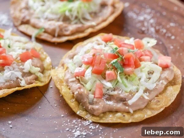 Walking Tacos: Portable Taco Cups for Parties and Snacks 5 Three tostadas topped with refried beans, lettuce, tomatoes, and cilantro.