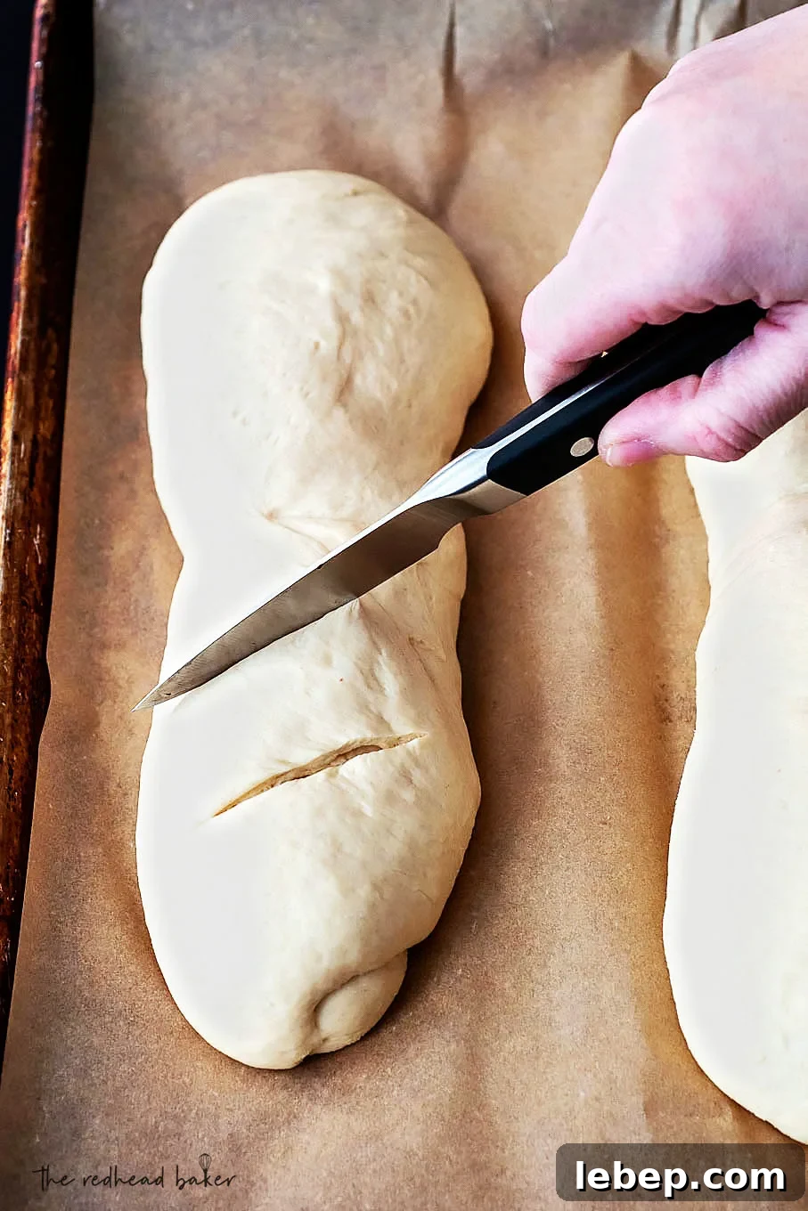 How to Bake Bread at Home: Classic Italian Bread Recipe 3 A loaf of bread being scored with a parking knife.