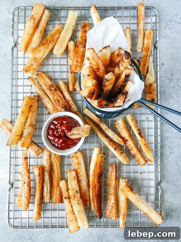 Baked yuca fries on a cooling rack with a small bowl of ketchup