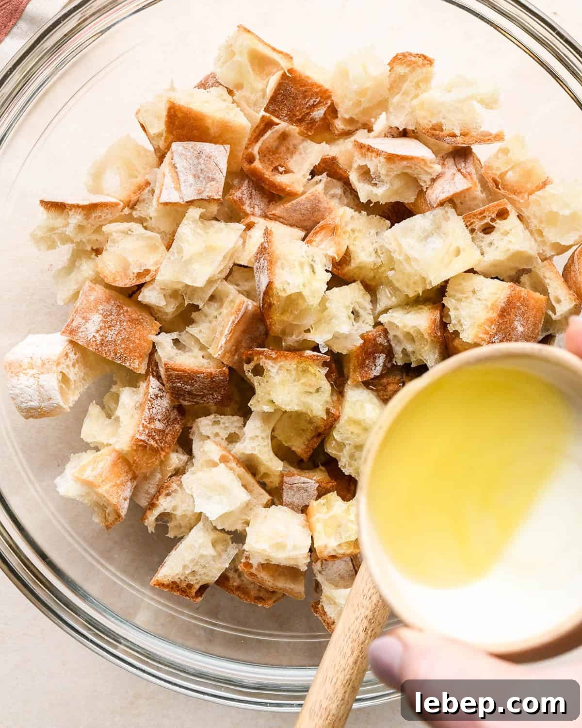 How to Make Croutons - pouring olive oil over bread cubes in a bowl