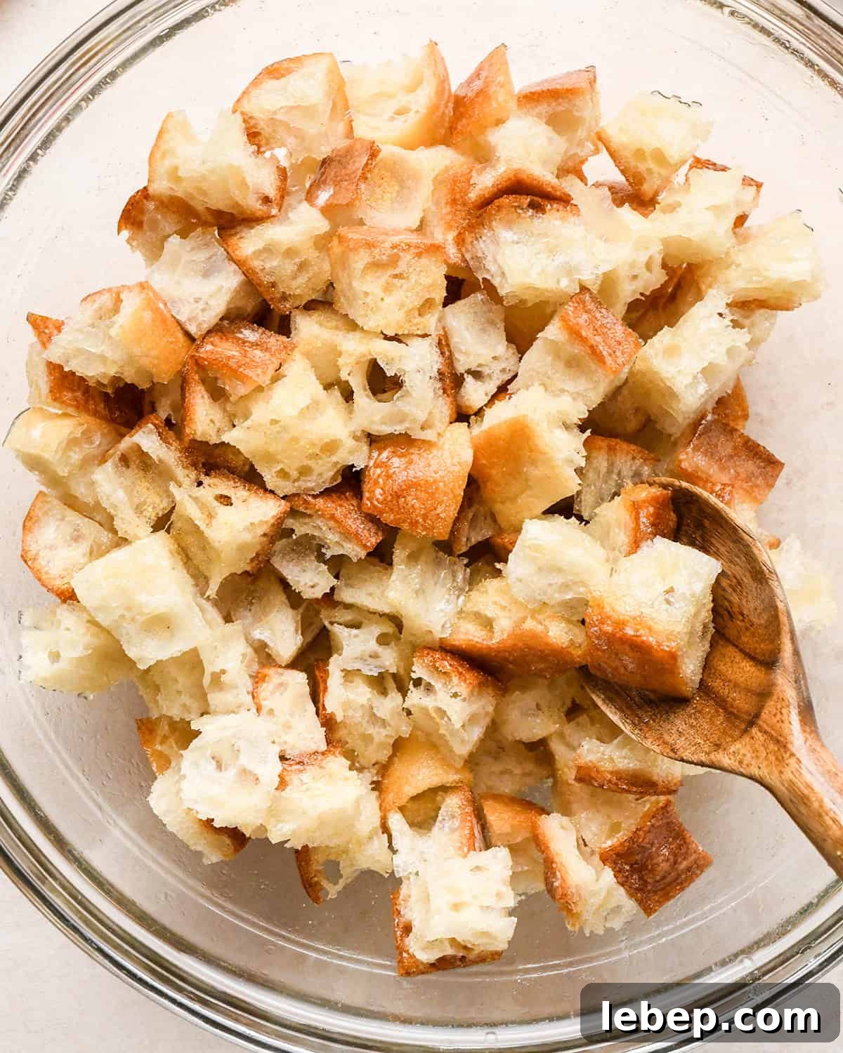How to Make Croutons - stirring spices into bread with a wood spoon in a bowl
