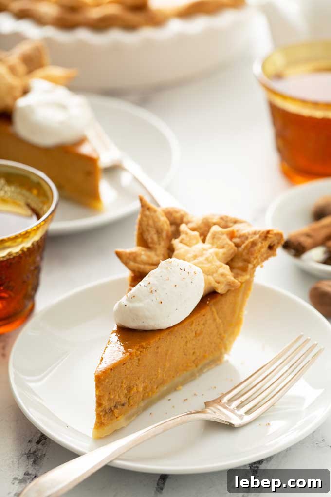 Slice of pumpkin pie topped with maple whipped cream on a white plate.
