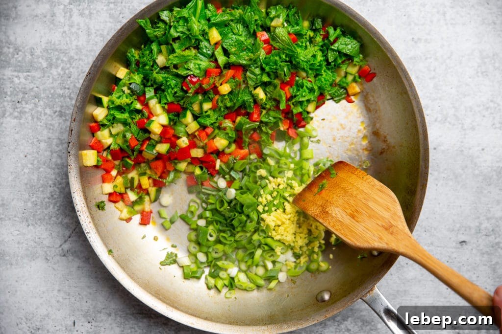 Process shot showing the vegetables cooking in a skillet for the salmon fried rice recipe. 