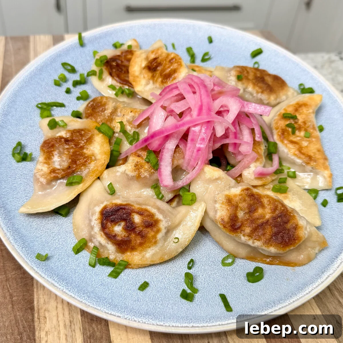 pulled pork pierogi placed with pickled red onion on top.