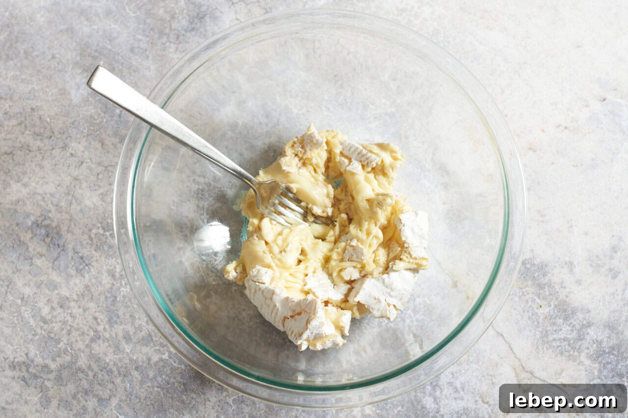 Mashed camembert cheese in a bowl with a fork.