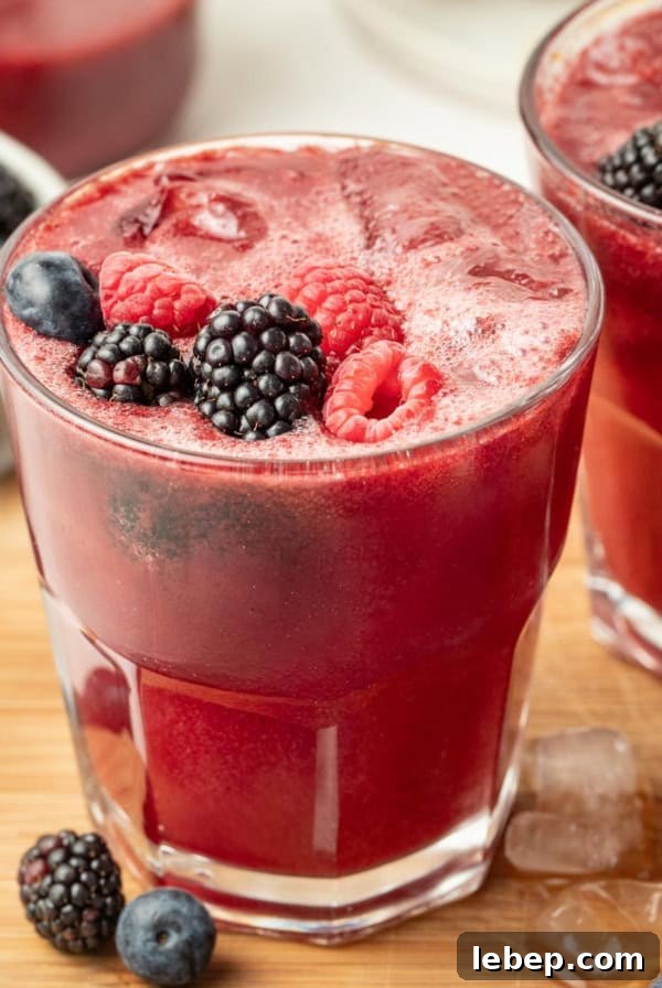 A mixed berry mocktail on a wood cutting board with fresh mixed berries on top.