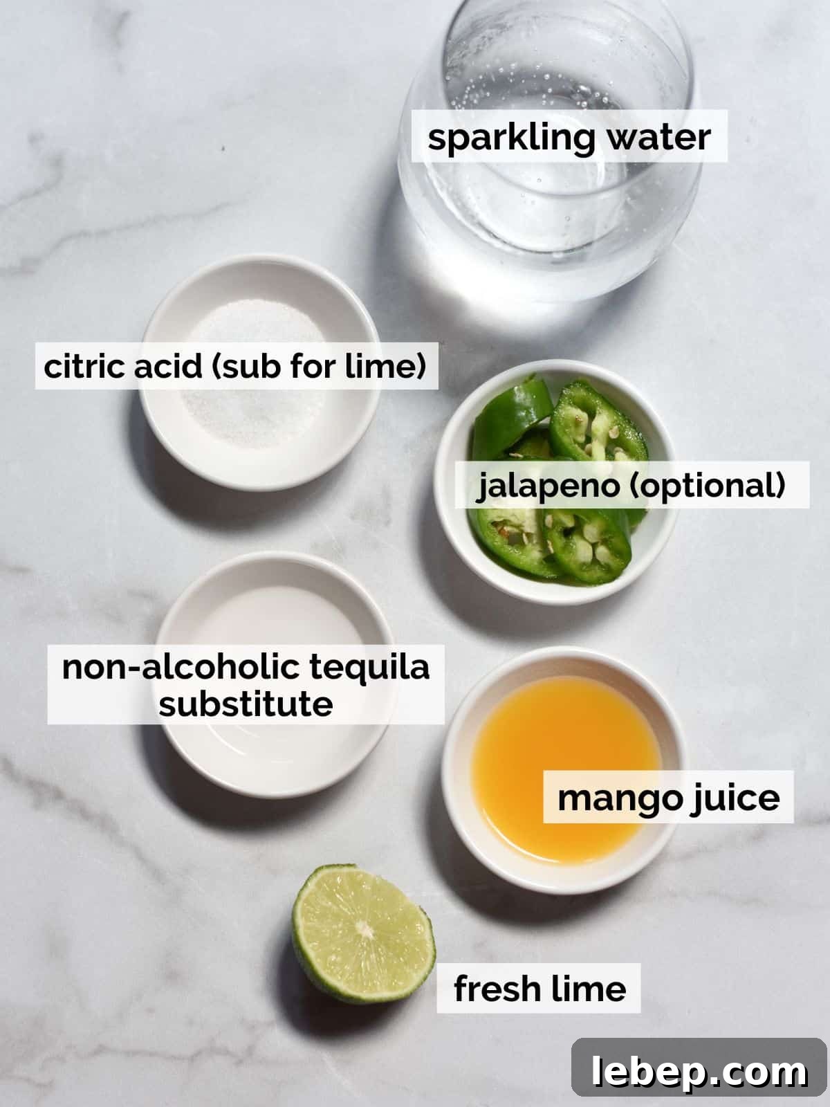 Ingredients for non-alcoholic margaritas on a white marble background.