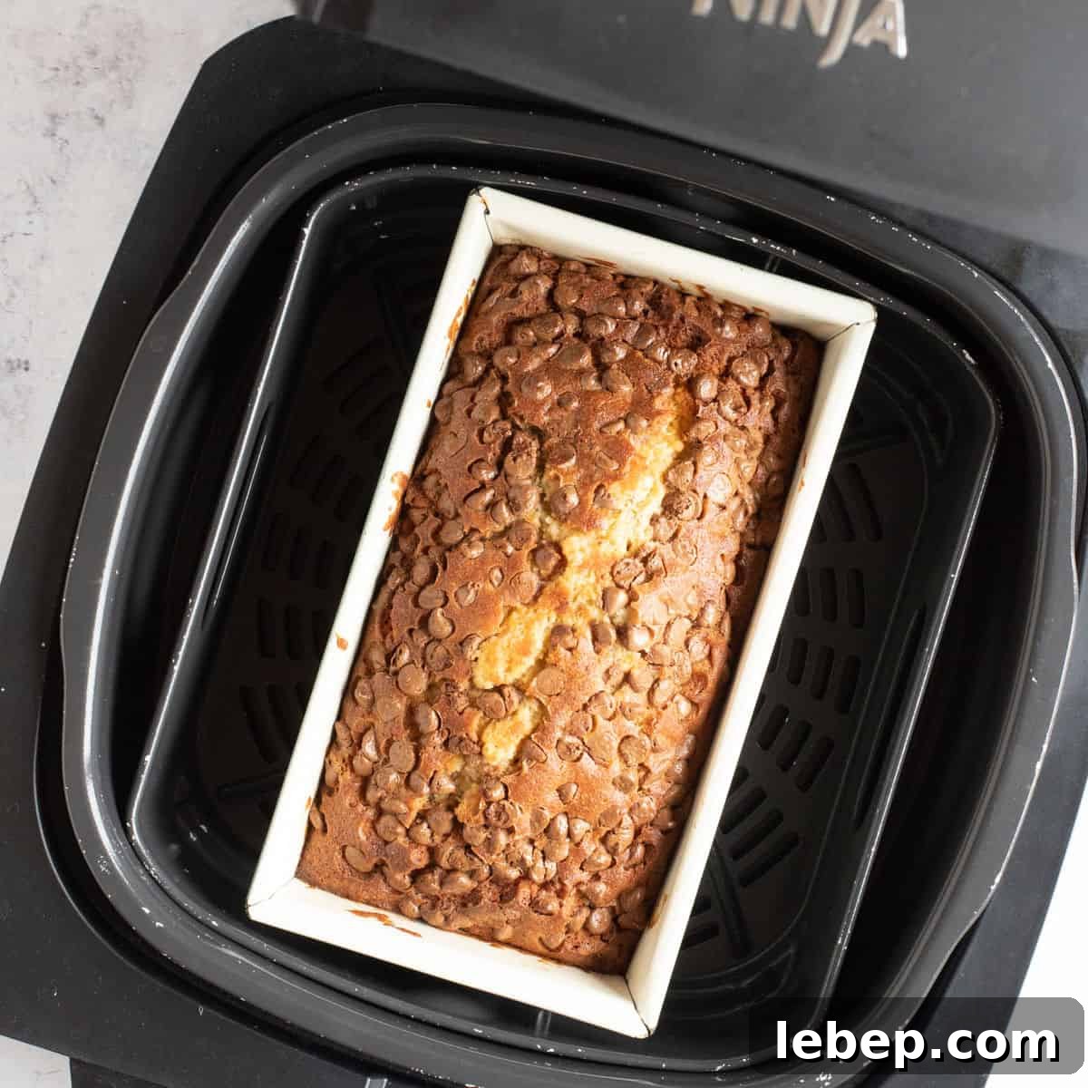 Air Fryer Banana Bread Recipe: Moist, Quick Loaf in 30 Minutes 10 Baked air fryer chocolate chip banana bread in air fryer basket.