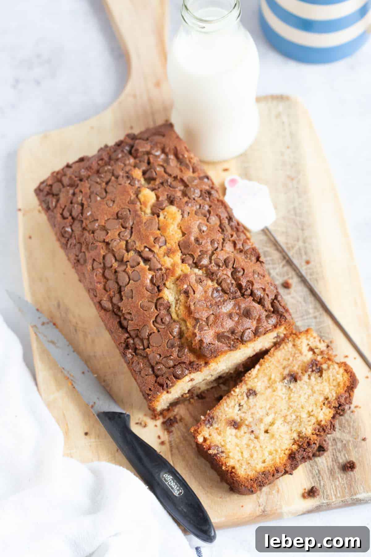 Air Fryer Banana Bread Recipe: Moist, Quick Loaf in 30 Minutes 12 Chocolate chip banana bread on a wooden board with a glass of milk in the background.