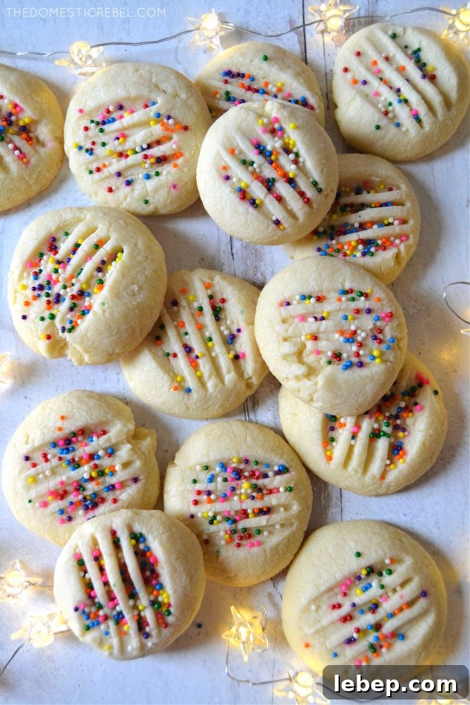 Arrangement of whipped shortbread cookies on white wood with twinkle lights