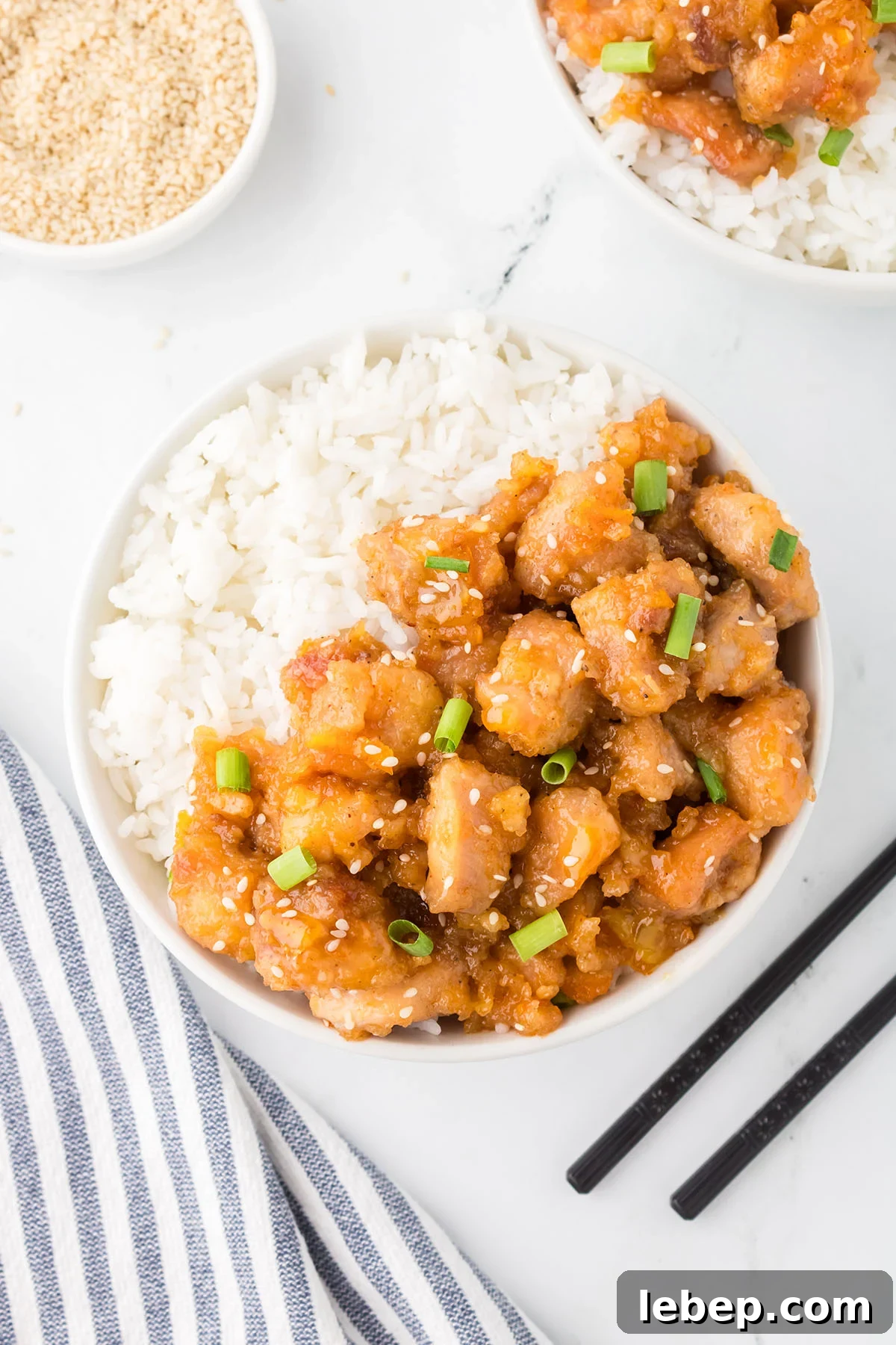 Orange Chicken served in a white bowl with rice.