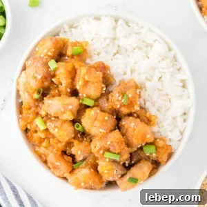 Orange Chicken and rice in a white bowl.