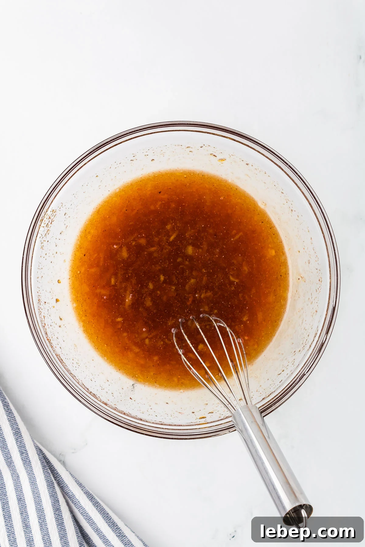 Orange marmalade, soy sauce, rice vinegar, onion powder, and chili powder mixed in a glass mixing bowl.